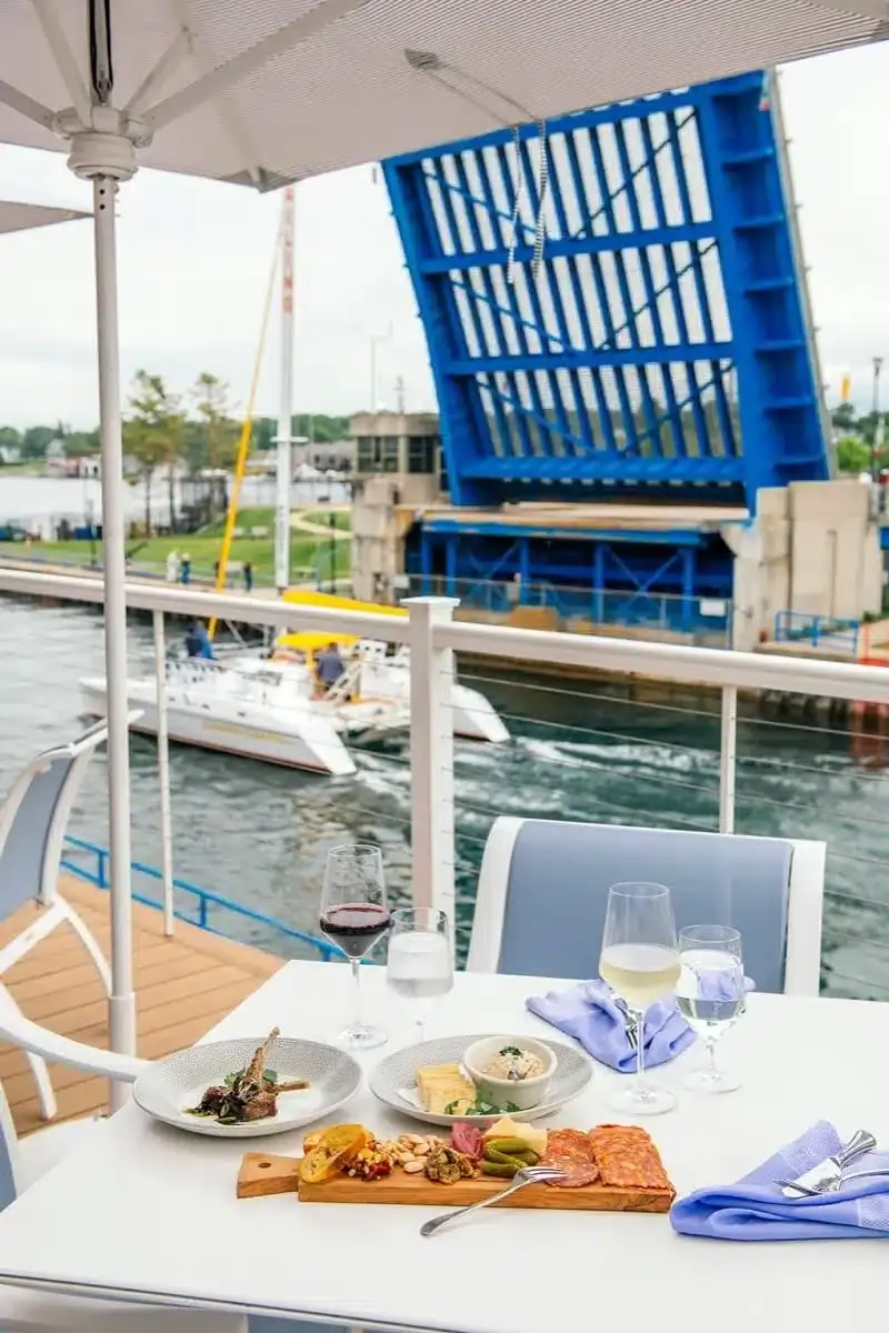 A board of cured meats and cheese with glasses of wine on the patio table, the drawbridge behind