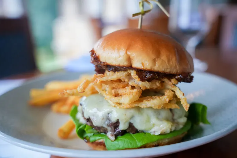 A burger topped with crispy onions, served with fries